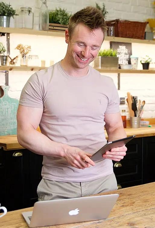 Scott laidler online fitness coach smiling with laptop computer in kitchen