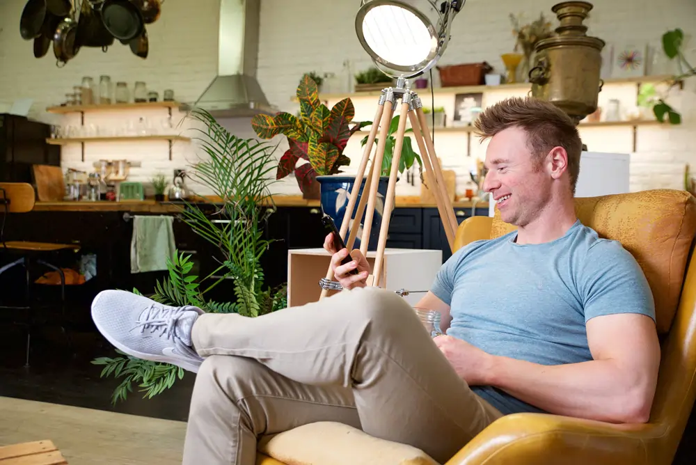 Fitness coach Scott Laidler interacting with clients on phone in modern open-plan living area