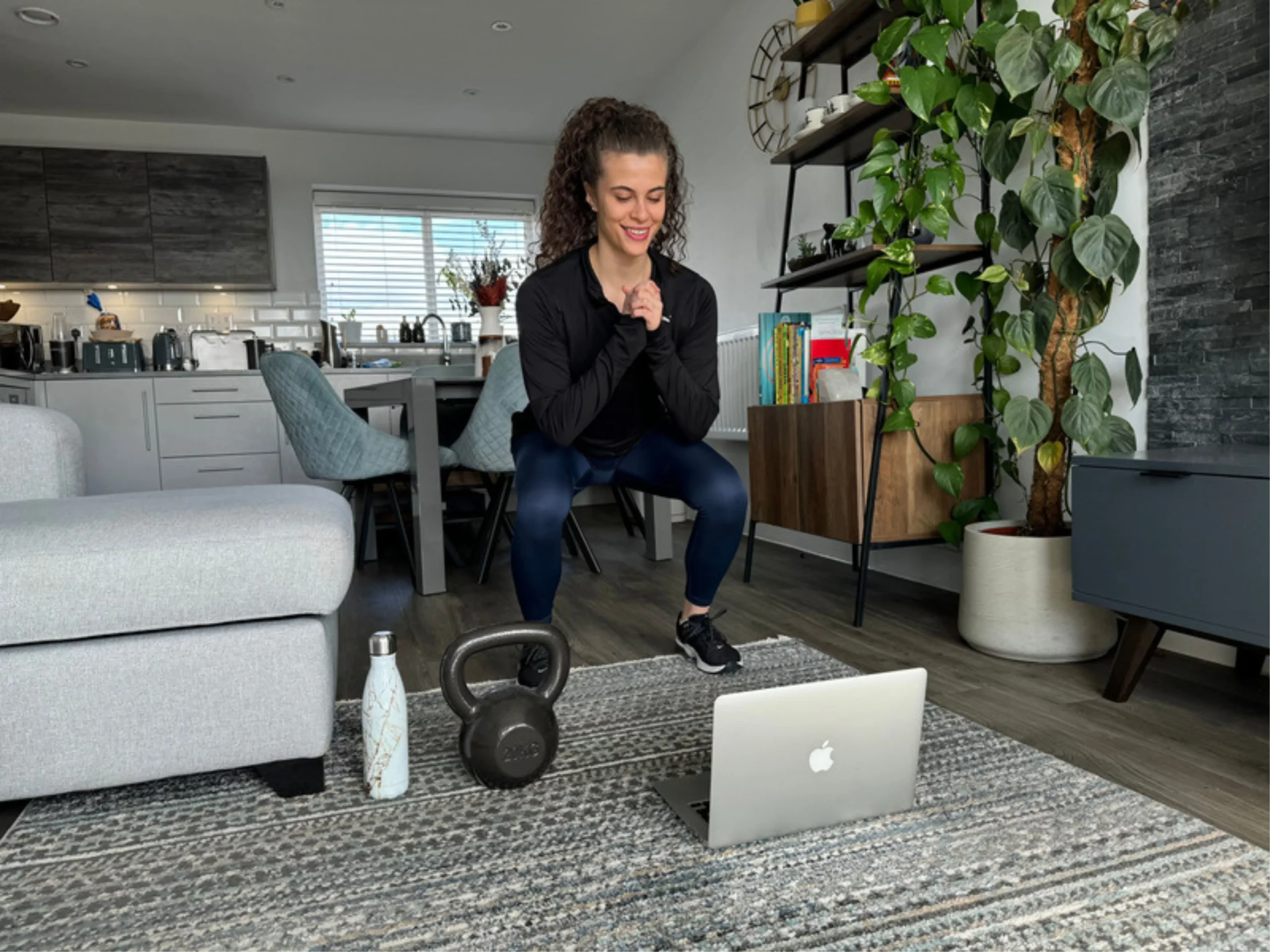 Young female client enjoying Scott Laidler online fitness program at home with kettlebell