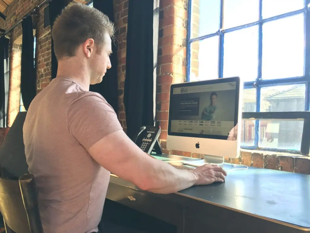 Online fitness coach Scott Laidler sitting working at a desktop computer